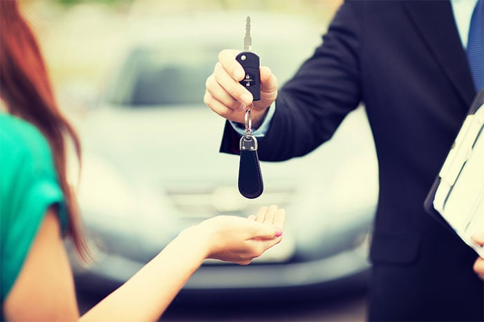 Car salesman handing keys to driver