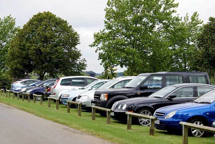 A row of various make and model cars parked behind a fence