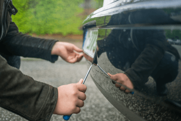 Someone trying to steal a car's number plate