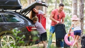 A family packing their suitcases into their hire car