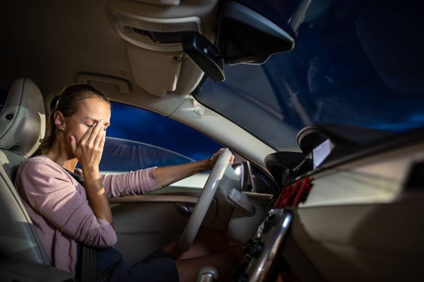 Person who's tired rubbing their eyes while driving