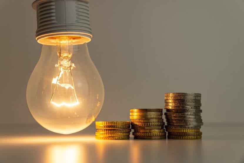 Lightbulb on with coins stacked up next to it