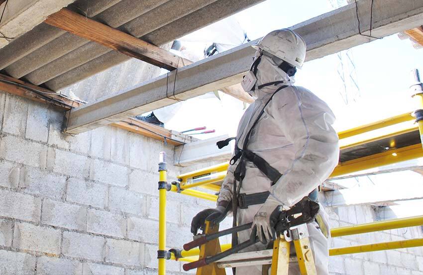 a man in a protective suit and mask inspecting a roof