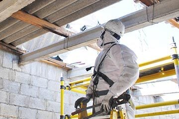 a man in a protective suit and mask inspecting a roof