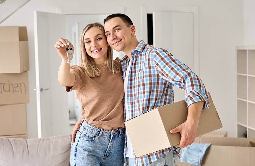 a couple standing in a room holding a set of house keys
