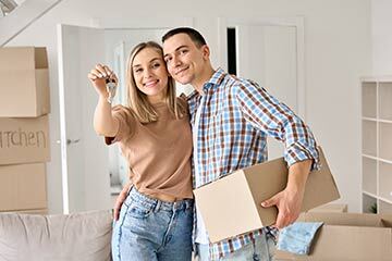 a couple standing in a room holding a set of house keys