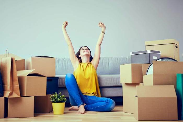 Woman sat on the floor surrounded by moving boxes
