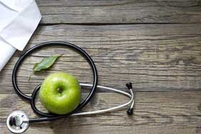 An apple and a stethoscope on a desk