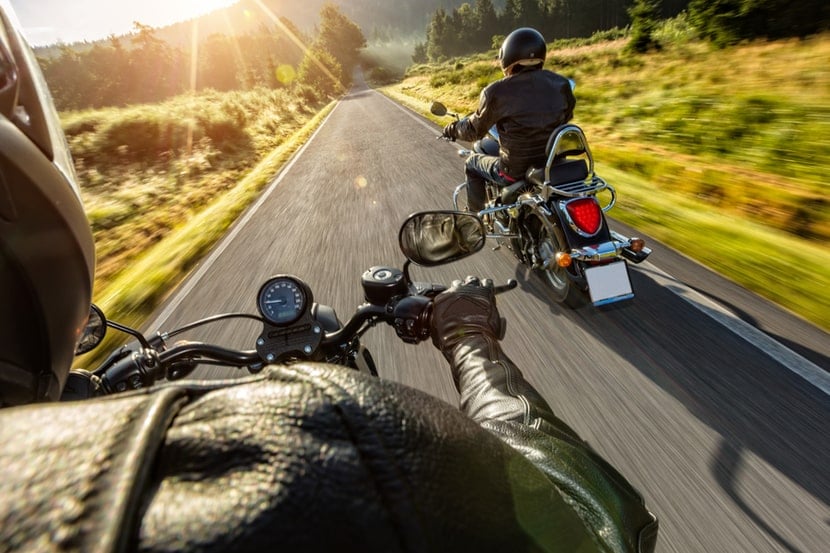 Two motorbikes ride down a country lane