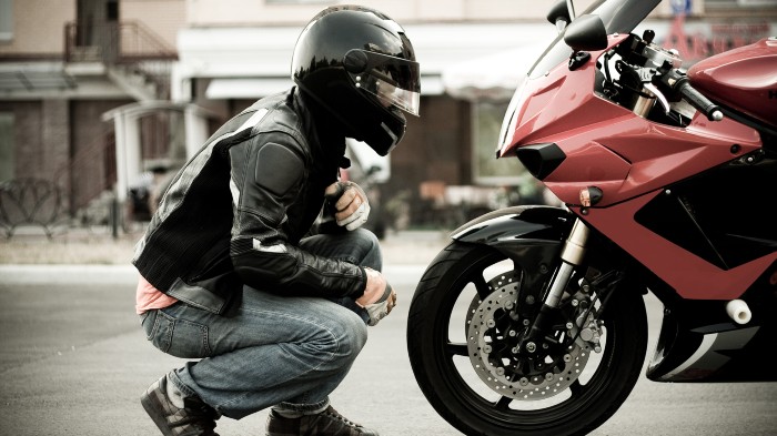 A motorcyclist inspects their motorbike