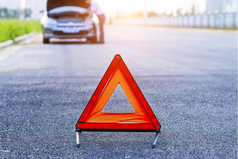 Red warning triangle placed on the road behind a broken down car