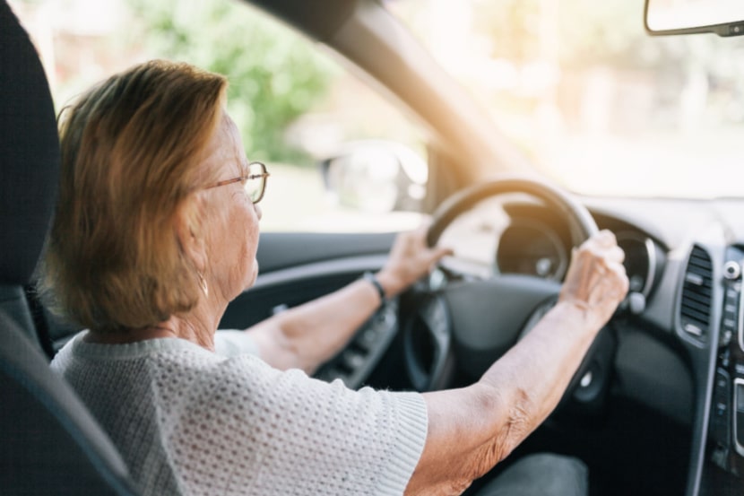 Older woman behind steering wheel driving a car