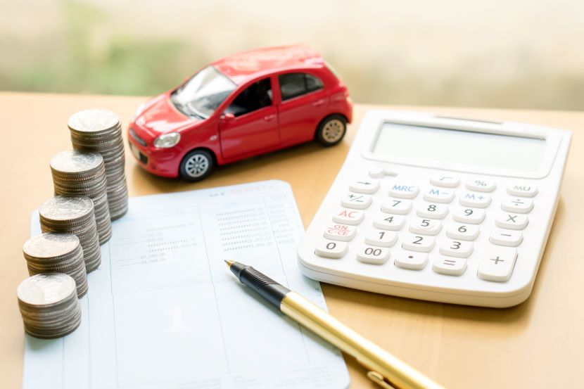 Model car on a table with coins and a calculator