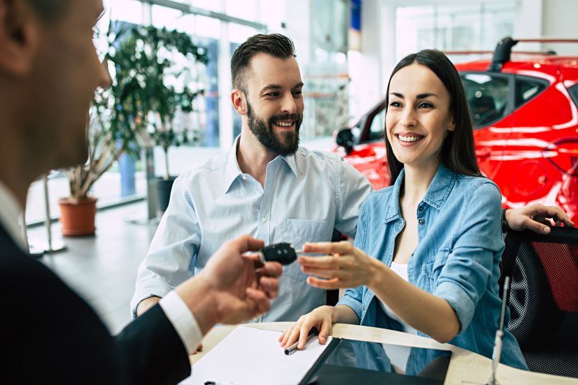 Smiling couple receiving the keys to their new car