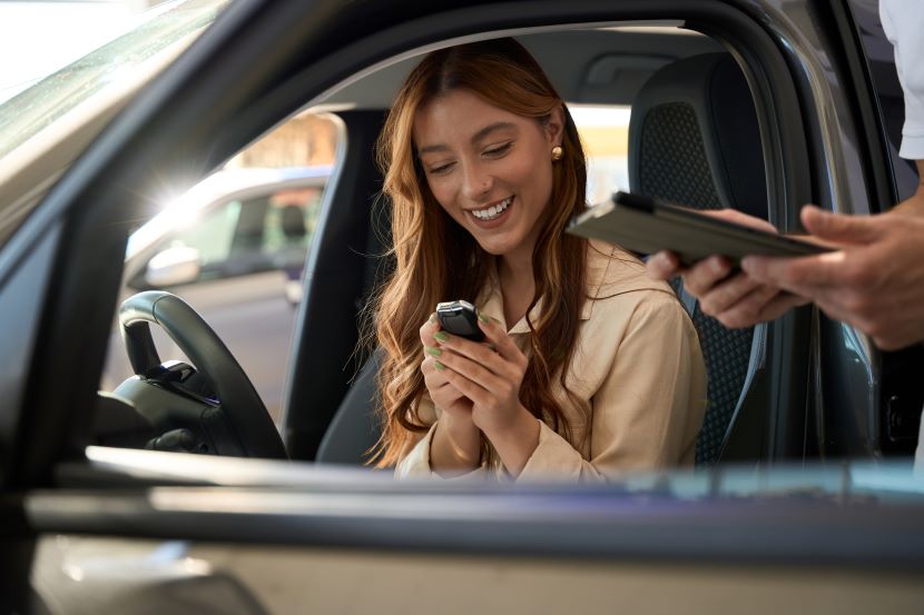 Women sitting in a car smiling as she holds the keys