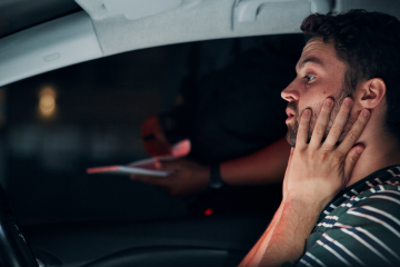 man stressed holding his face while in car