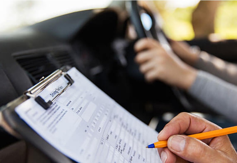 An instructor ticks a driving test checklist 