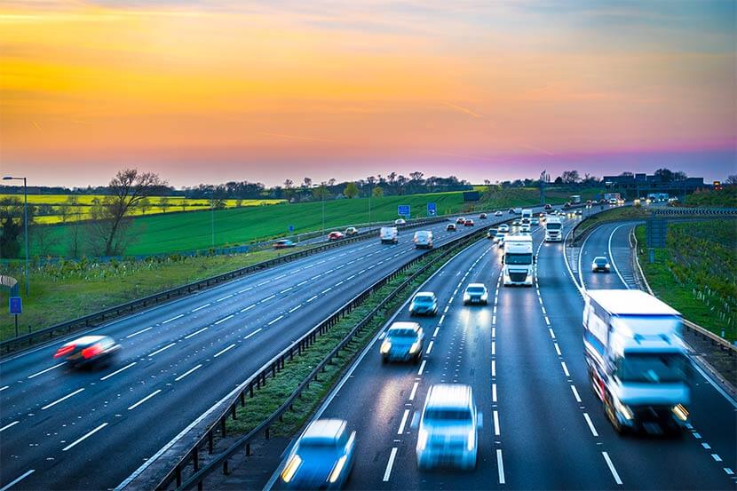 A rush of cars on a busy motorway at sunset