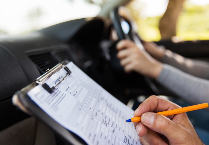 An instructor marks a student during their driving test