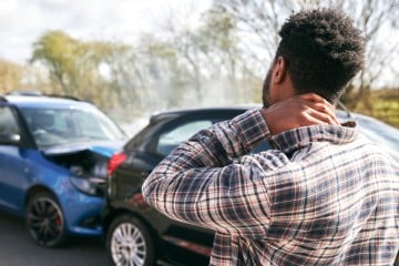 Driver rubbing neck after car accident, with possible whiplash