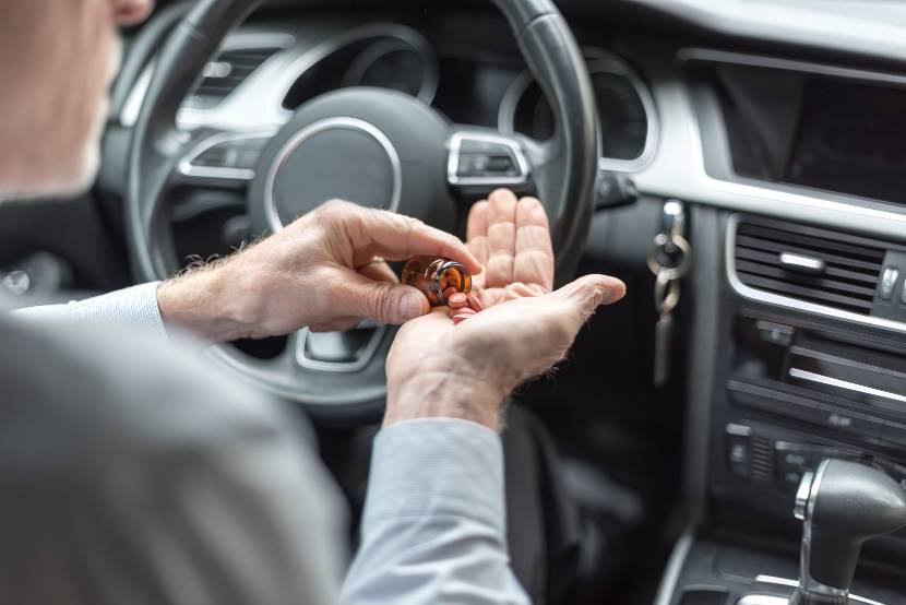 Driver tipping medication into their hand while sitting in the car