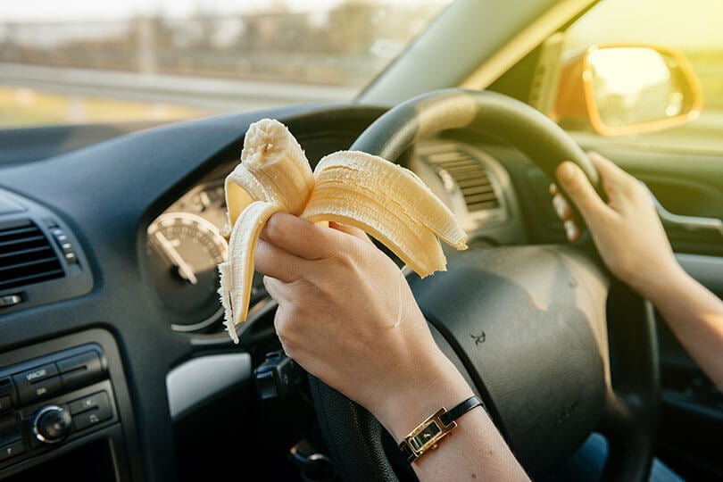Person eating a banana while driving