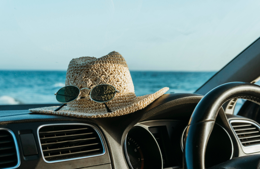 Summery straw hat with sunglasses on a car dashboard