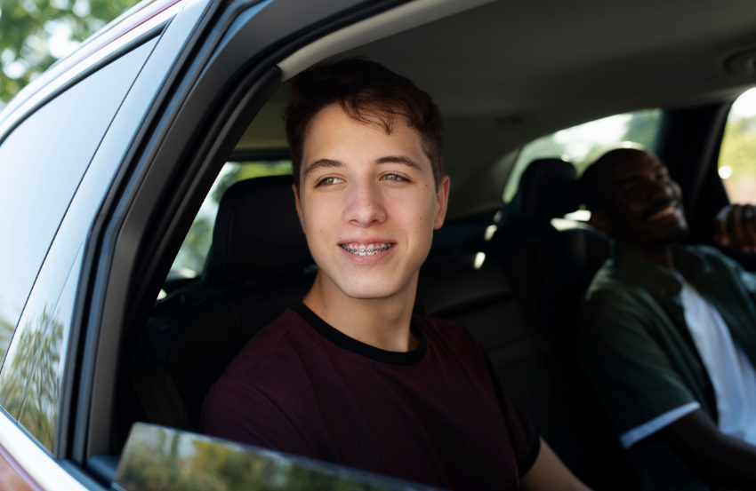 Teenager smiling while sitting in the driver seat of car