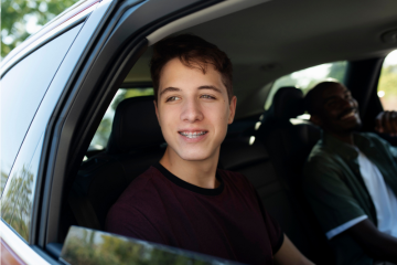 Teenager smiling while sitting in the driver seat of a car
