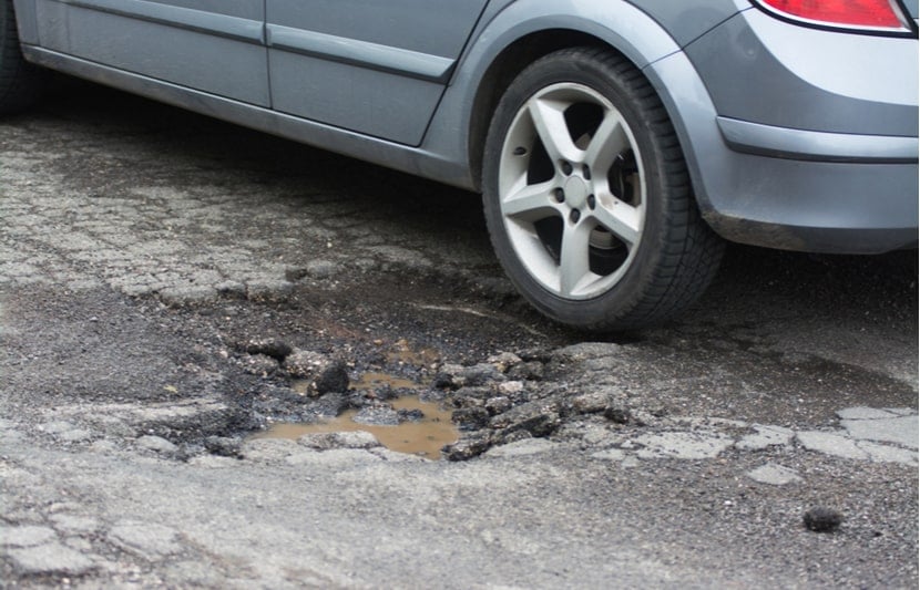 A car next to a pothole