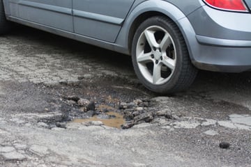 A car next to a pothole