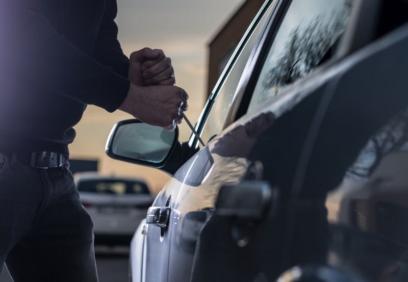 A thief breaking into a car