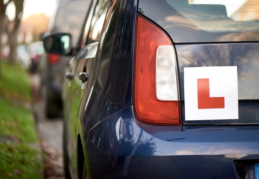 A parked car with a learner sticker on rear bumper