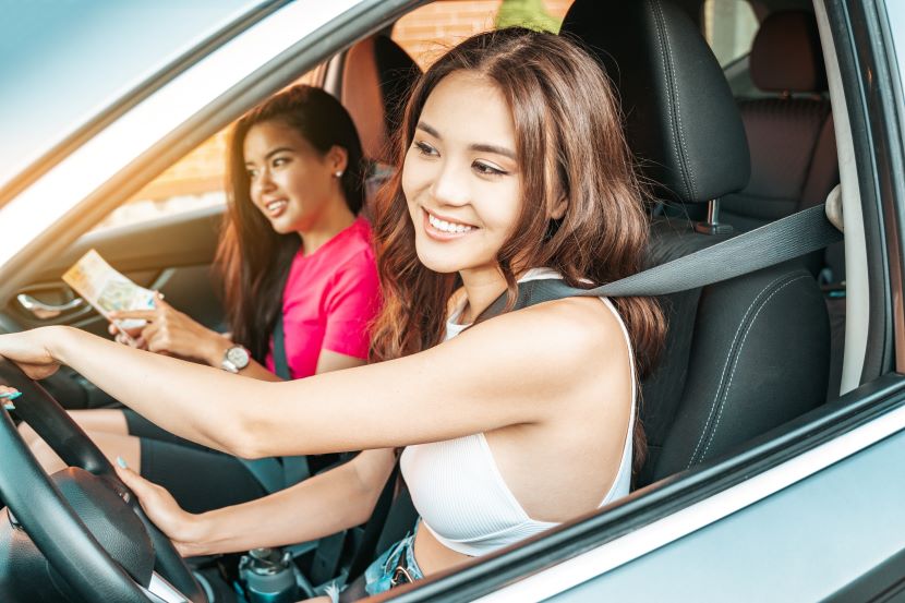 Two female students sitting in a car smiling.