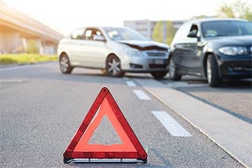 Two cars have crashed and there is a sign up alerting people to it