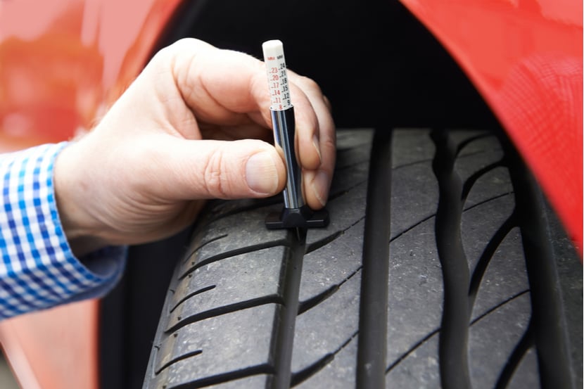 A close up of a driver checking their tyre tread depth