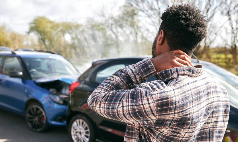 Man in check shirt holding his neck with possible whiplash after road accident 