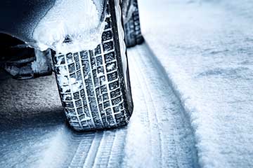 A close-up of a car with winter tyres driving on snow