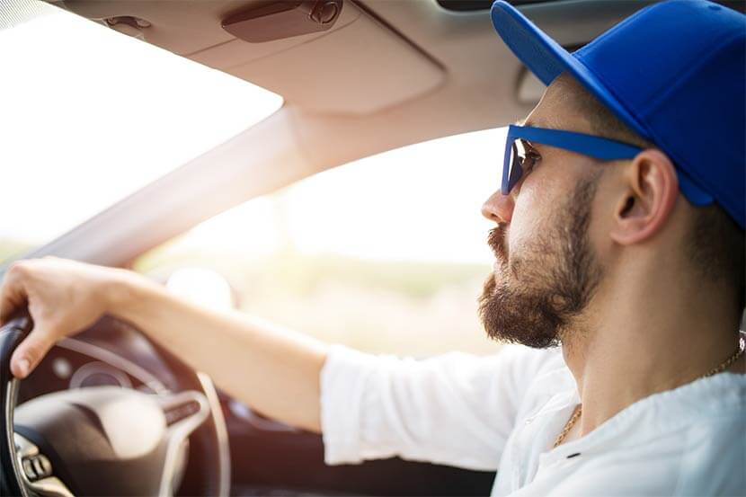 Young driver with hat driving in sunshine