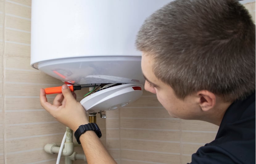 A boiler cover repairperson fixes a boiler