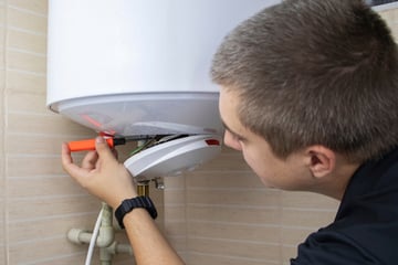 A boiler cover repairperson fixes a boiler