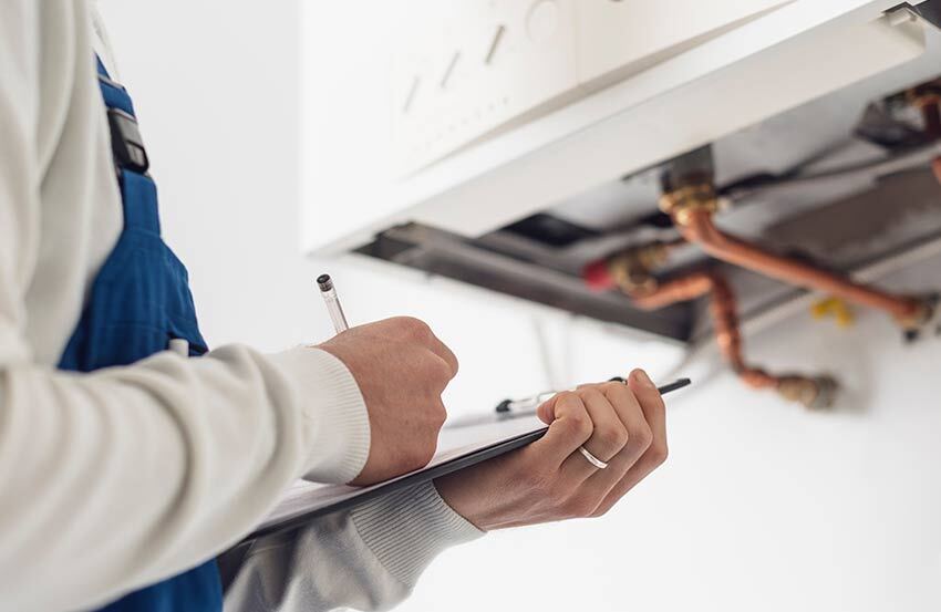 Plumber assressing a boiler with a checklist in hand