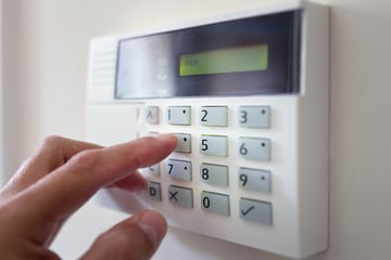 A homeowner enters sets their burglar alarm 