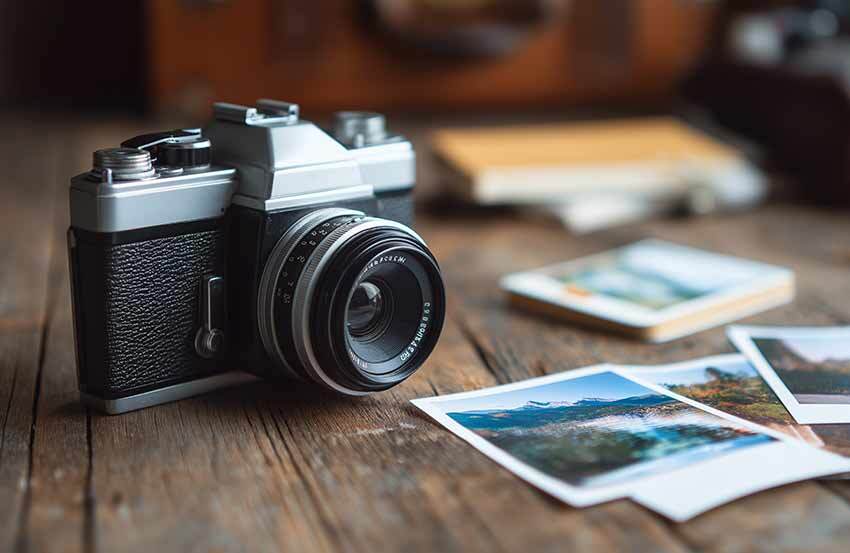 Camera resting on wooden floor boards, with polaroid-style printouts scattered around it