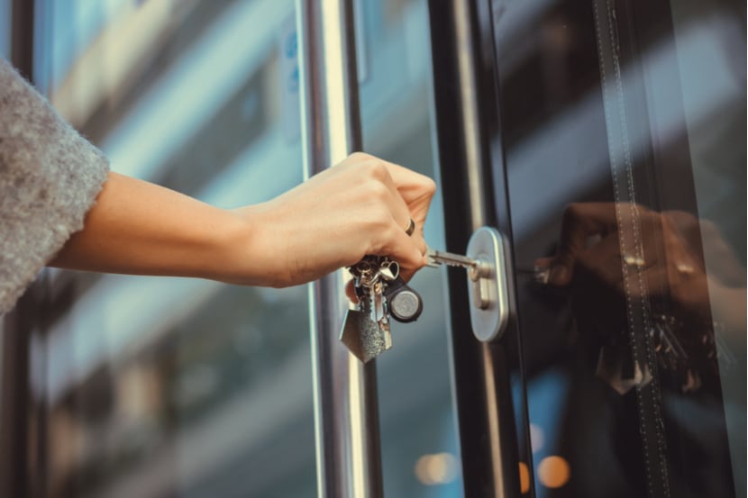 A woman puts a key in her front door lock