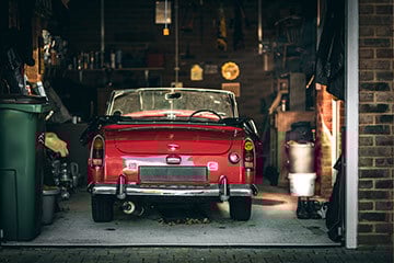 Shot of a red convertible car parked in a garage, taken from behind