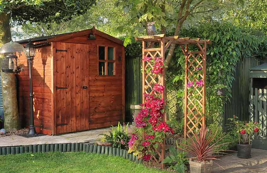 A shed and a trellis with flowers in a garden