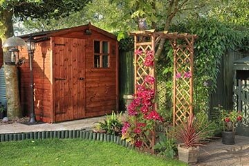 A shed and a trellis with flowers in a garden