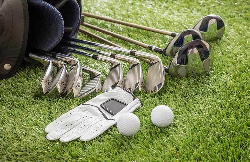 Golf clubs, ball, glove and bag laid out on grass