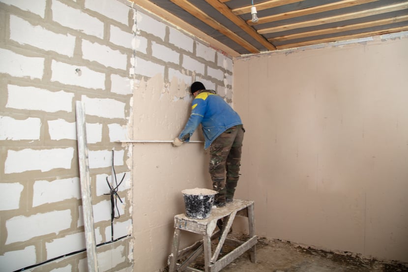 A tradesperson plasters a wall